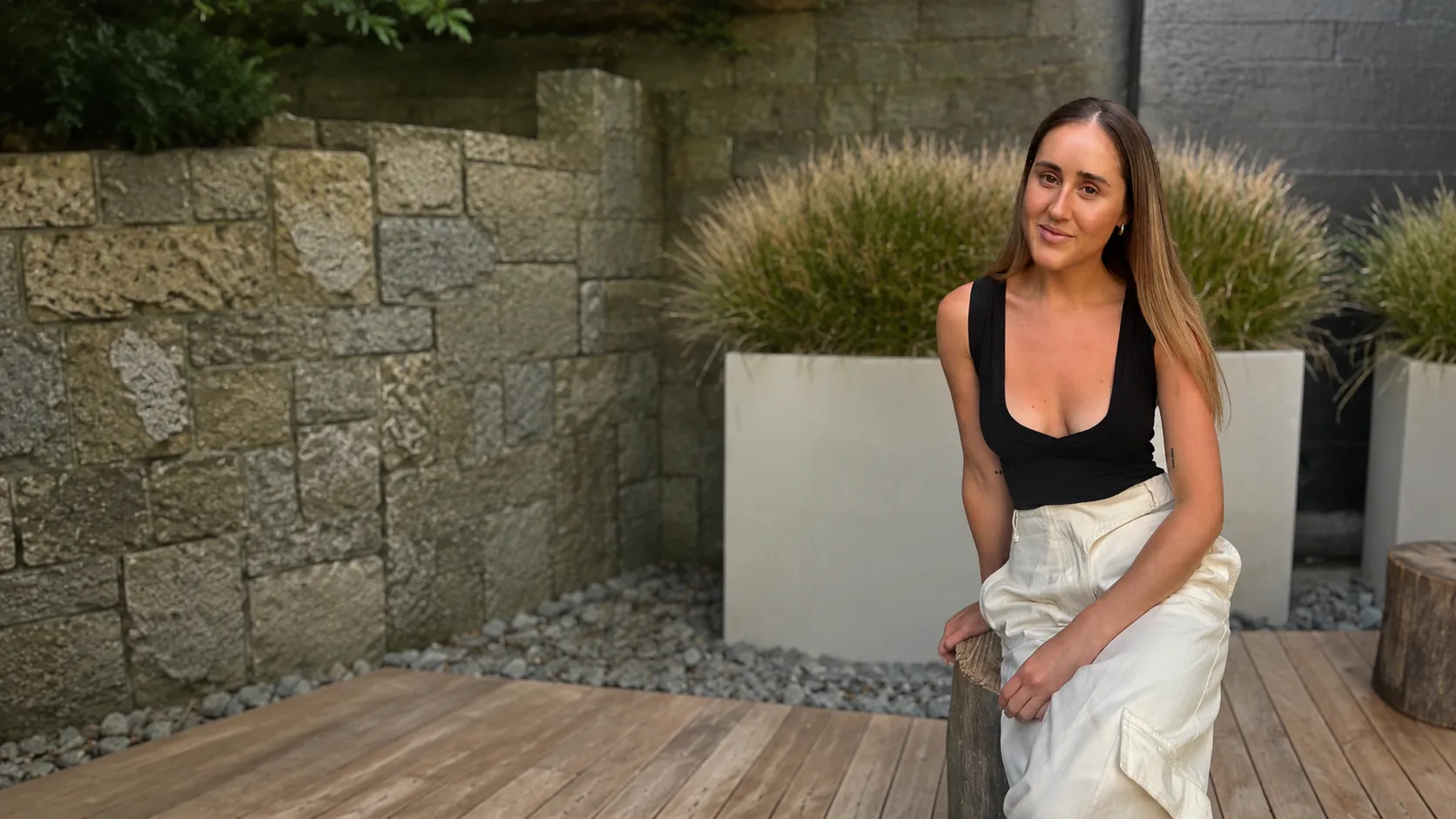 Brooklyn, a Hey Human member, seated beside a stone wall